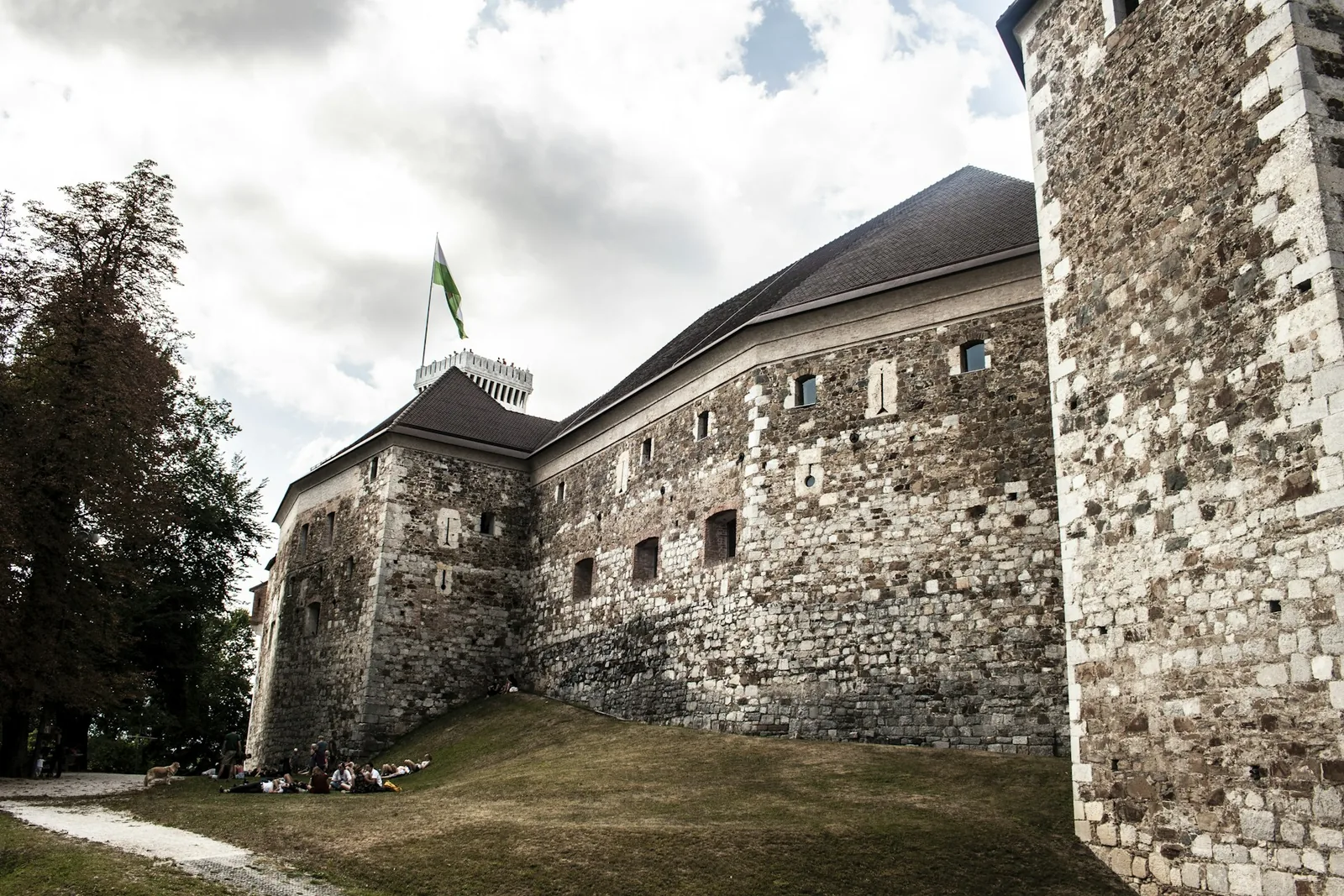 The stone walls and tower of Ljubljana Castle on its hilltop, the Slovenian flag flying above the courtyard